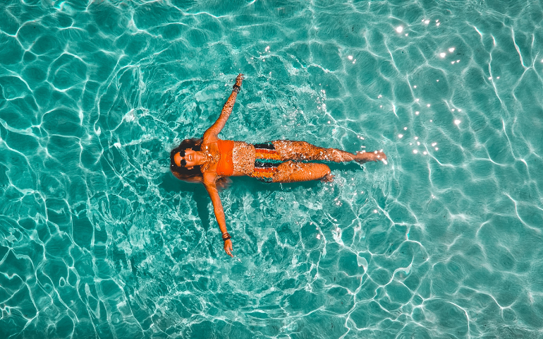 Jeune femme qui nage sur le dos avec des lunettes de soleil.