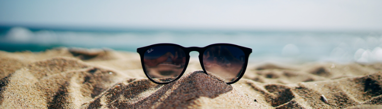 Le sable fin d'une plage, le soleil et des lunettes de soleil sont des signes de vacances.